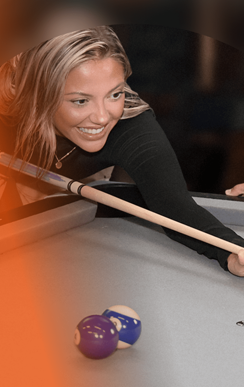 Woman playing pool with a focus on her face and the pool table.