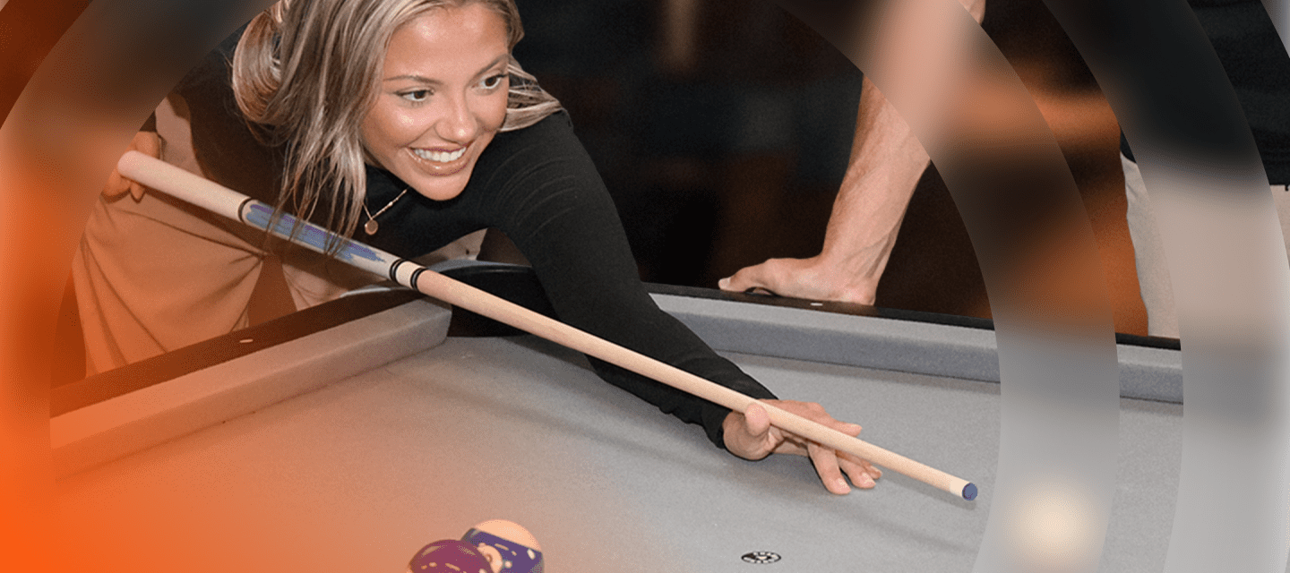 Woman playing pool with a focus on her and the pool table.